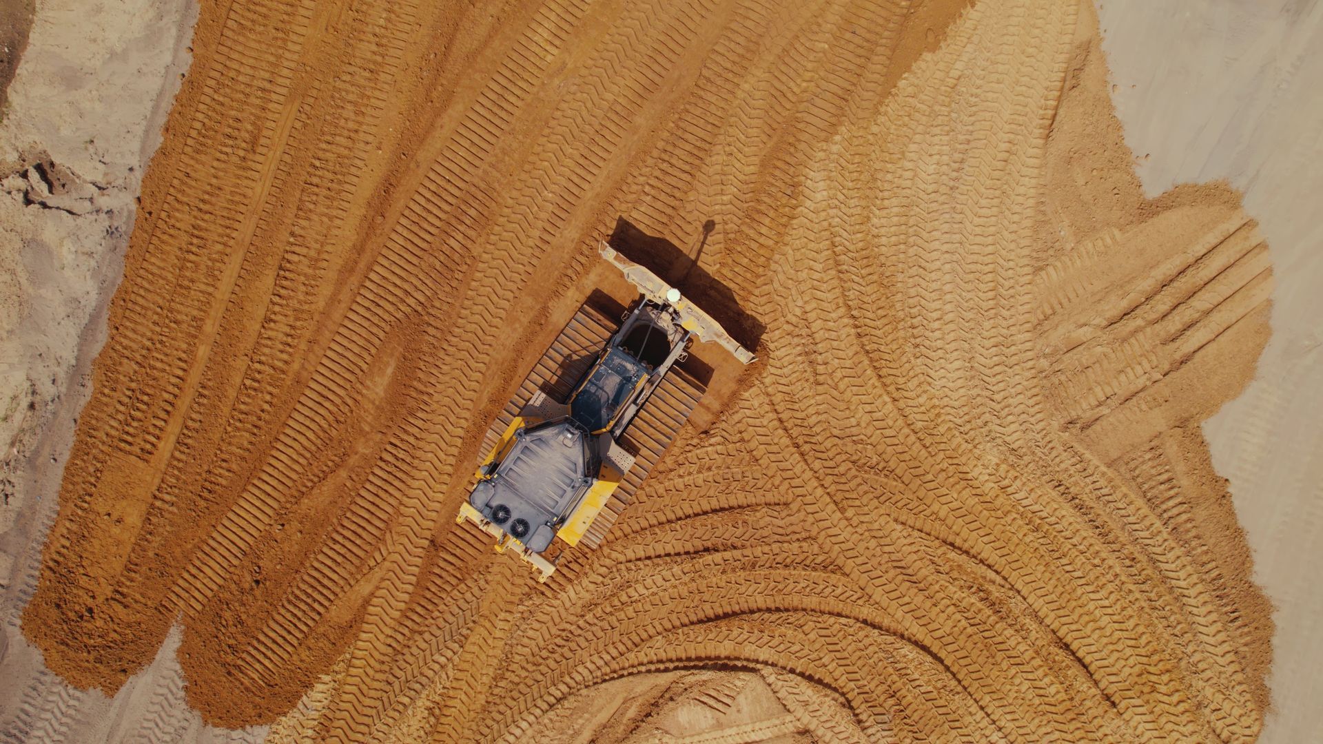An aerial view of a bulldozer moving dirt on a construction site.