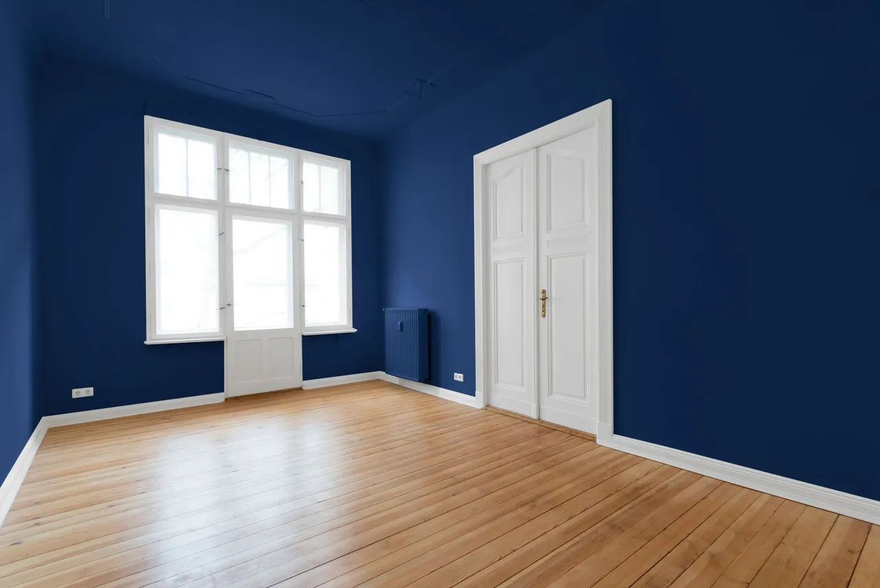 an empty room with blue walls and wooden floors