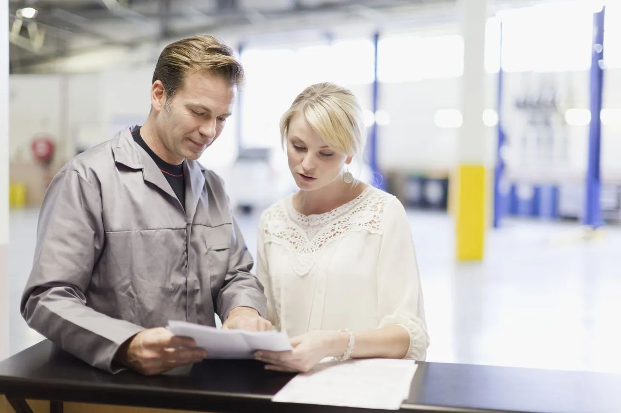 a man and a woman are looking at a piece of paper in a garage