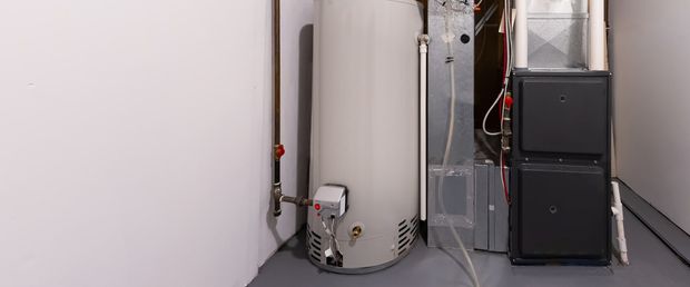 A water heater and a furnace are in a basement.