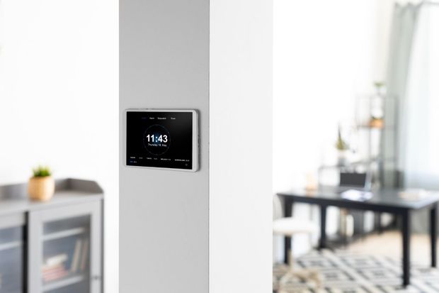 A smart thermostat is mounted on a wall in a living room.