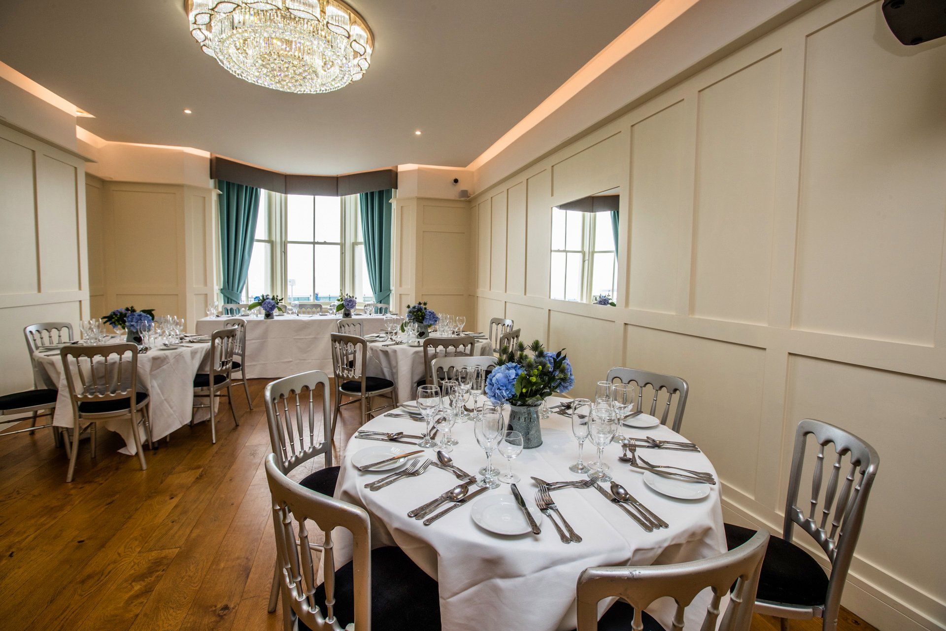 A dining room with tables and chairs set up for a wedding reception.