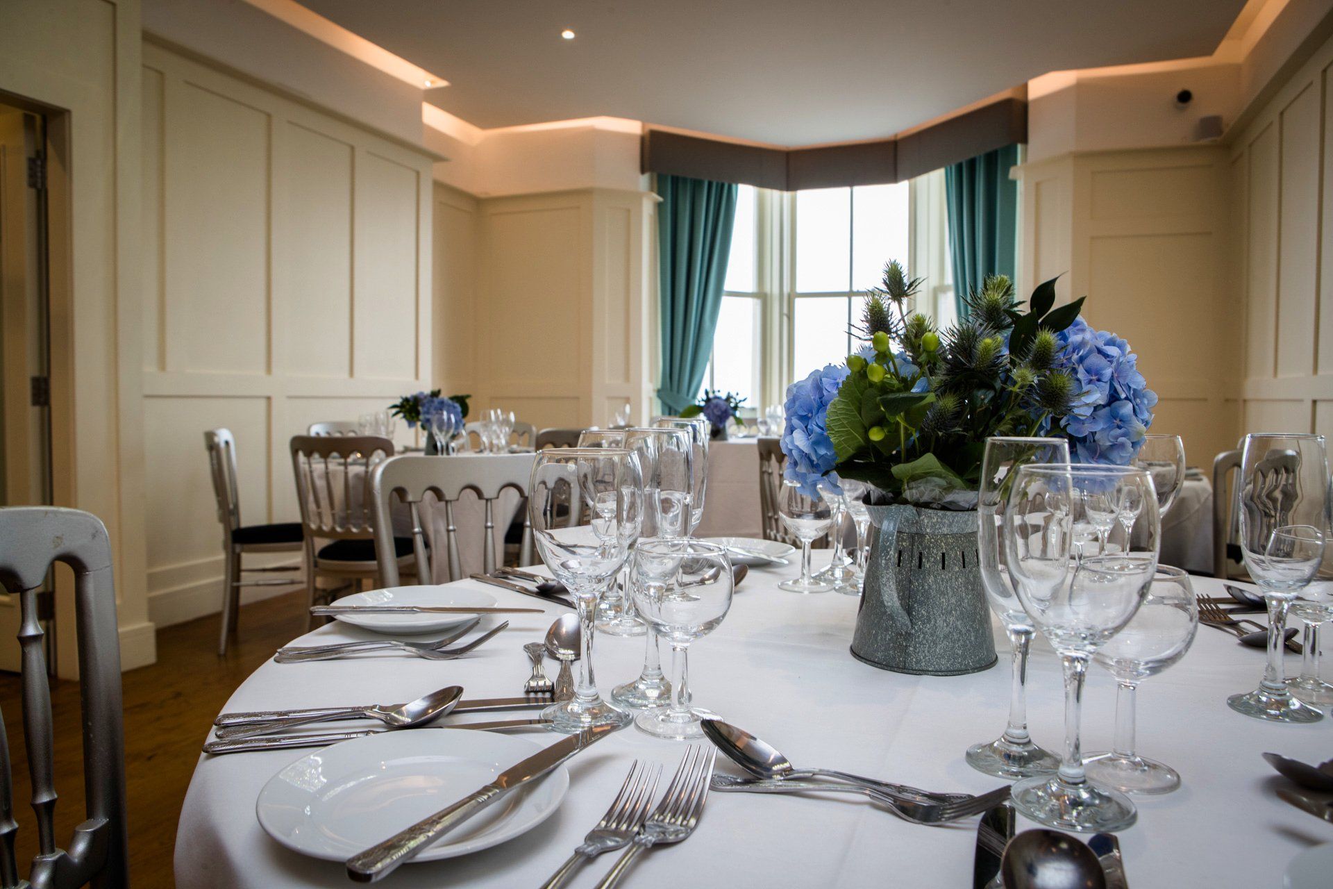 A table with plates , utensils , wine glasses and a vase of flowers on it.