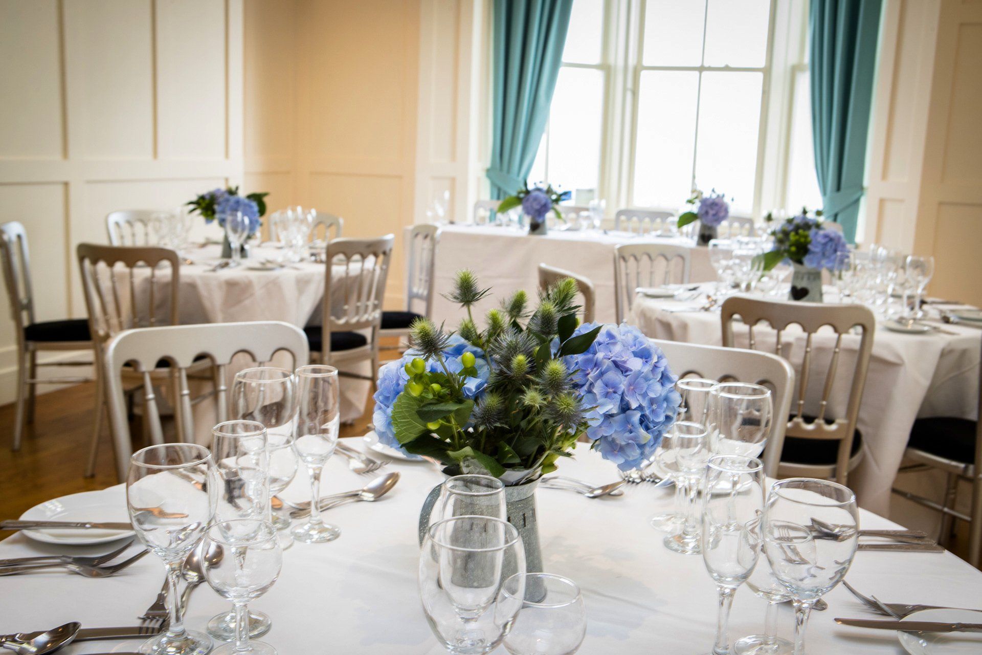 A table set for a wedding reception with a vase of flowers on it.