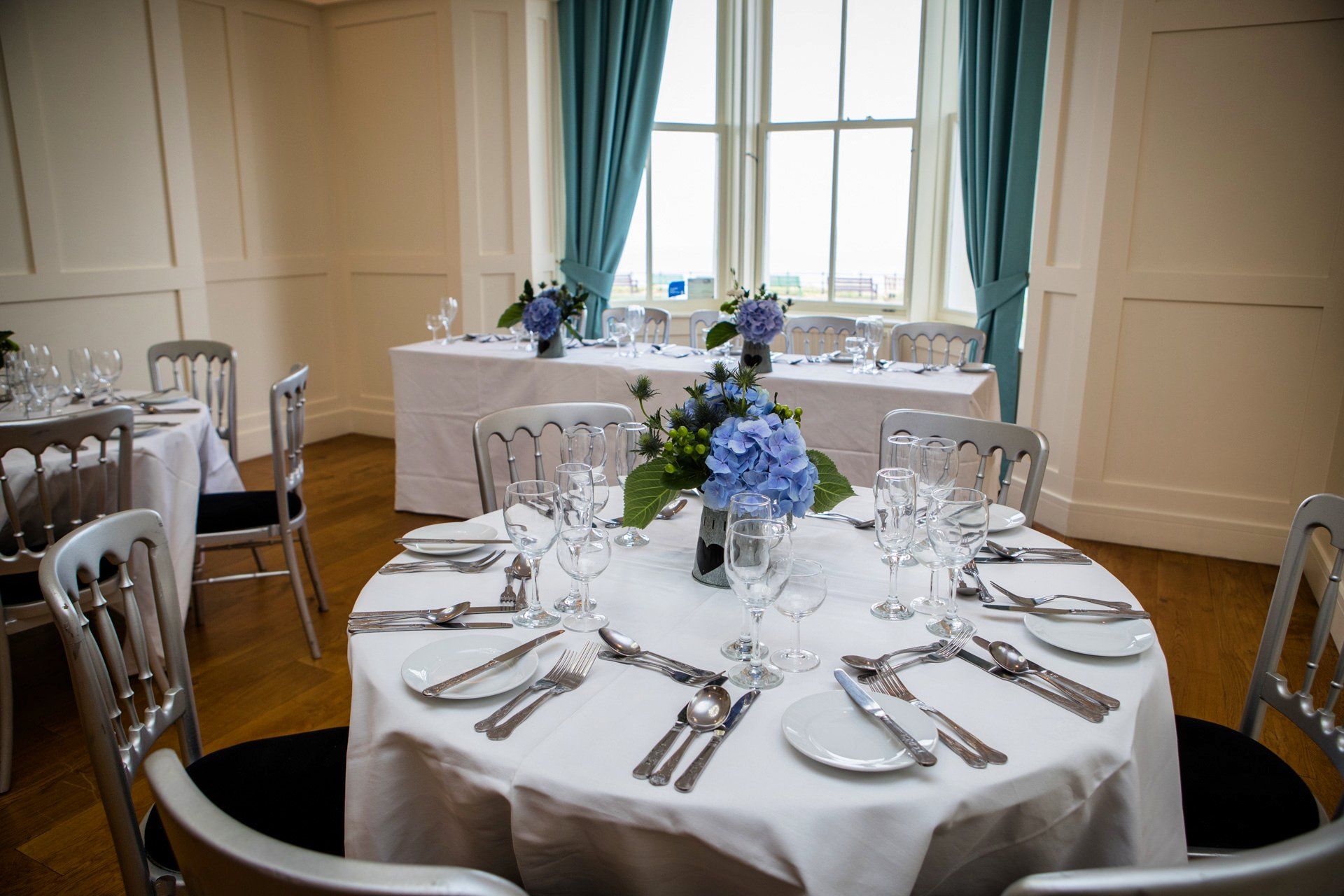 A room with tables and chairs set up for a wedding reception.