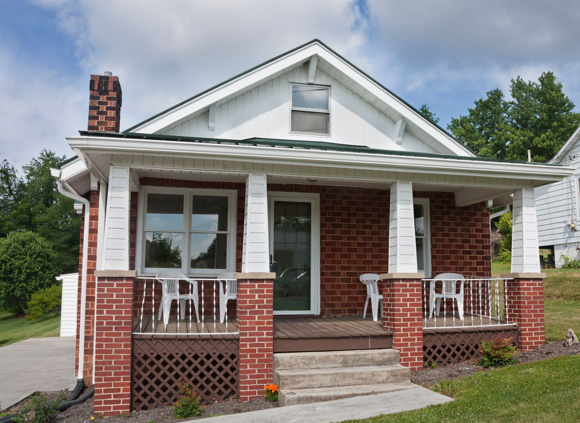 Red brick house with porch, white trim, and a small front yard.