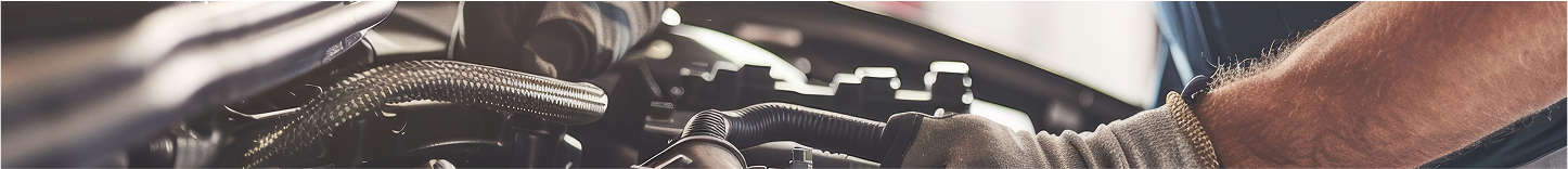 A person's gloved hand working on a car engine. | Deville Automotive