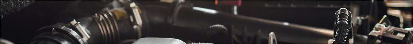 Close-up of engine parts. Dark gray and black metal components. Red parts on top. | Deville Automotive