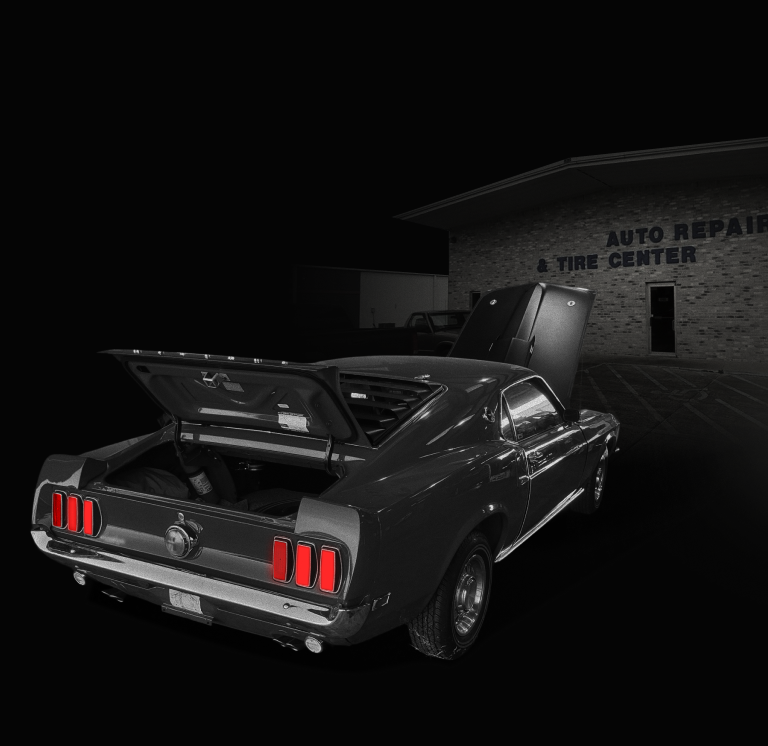 A blue sports car is parked in front of a garage door | Deville Automotive