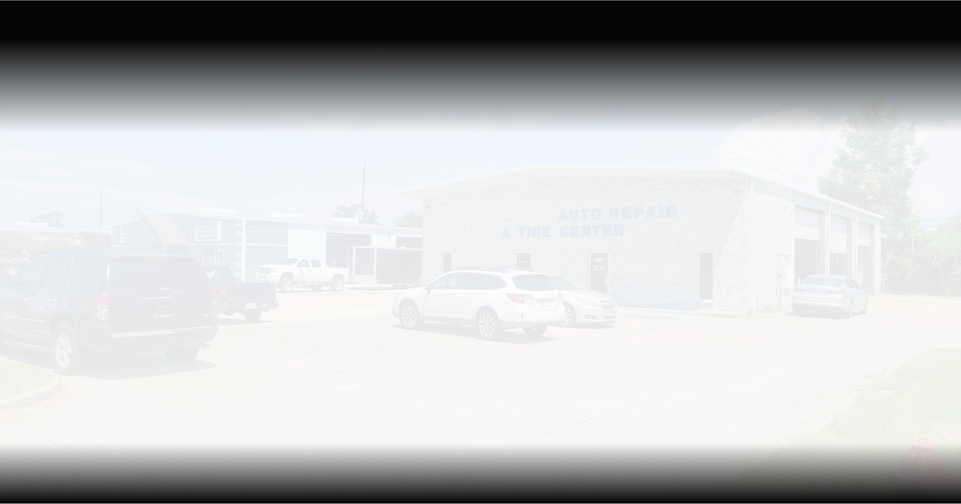 White building with cars parked outside. | Deville Automotive
