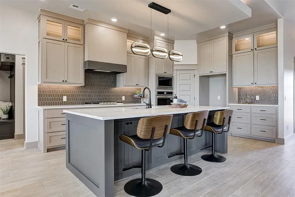A kitchen with white cabinets and a large island in the middle.