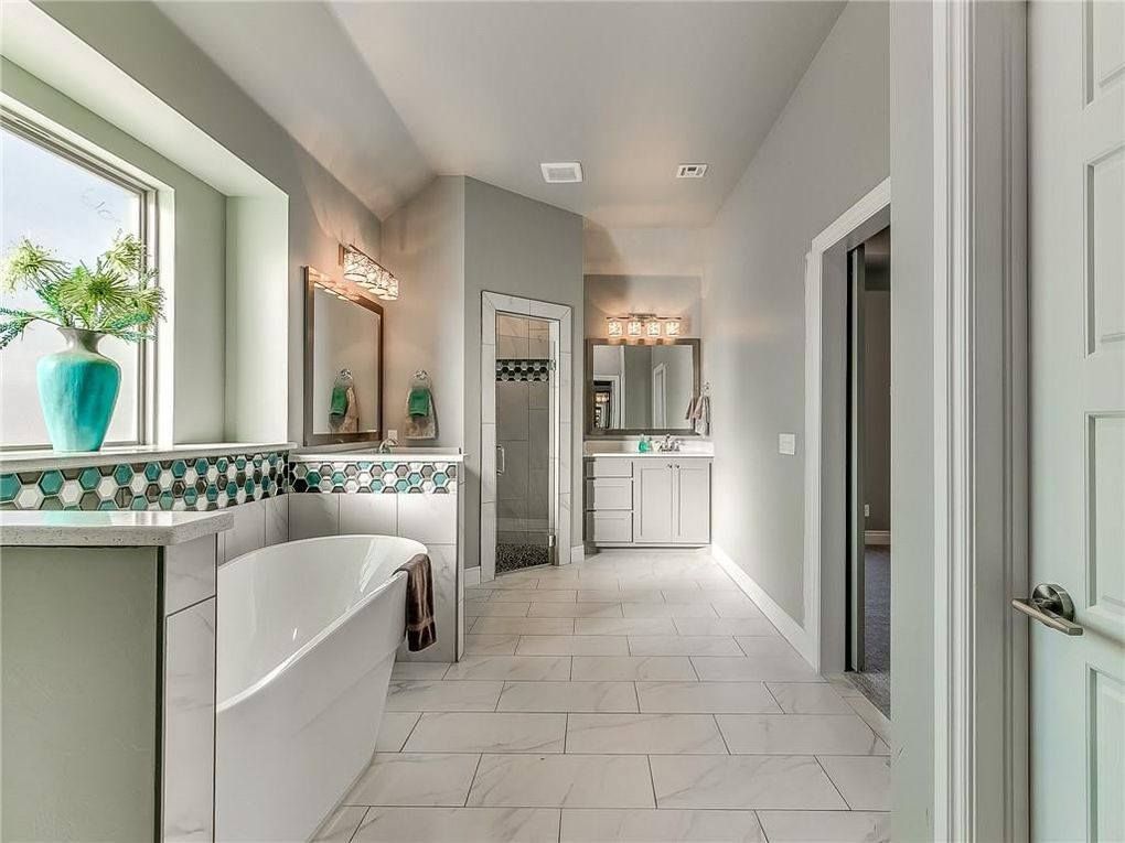 A bathroom with a tub , sink , mirror and window.