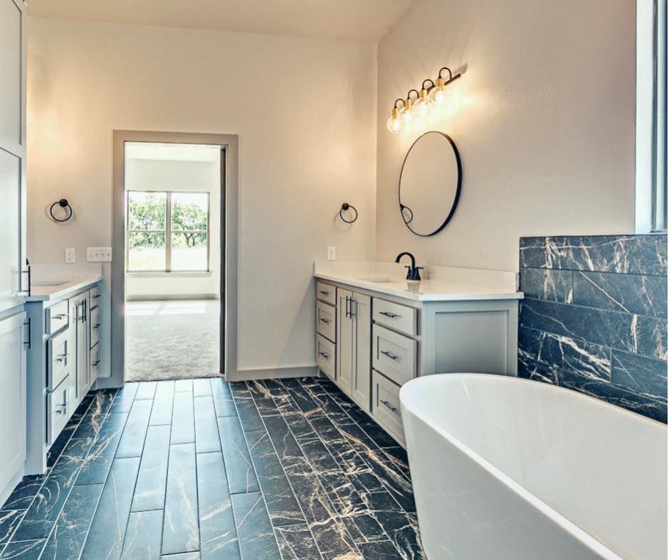 A bathroom with a tub , sink , mirror and cabinets.