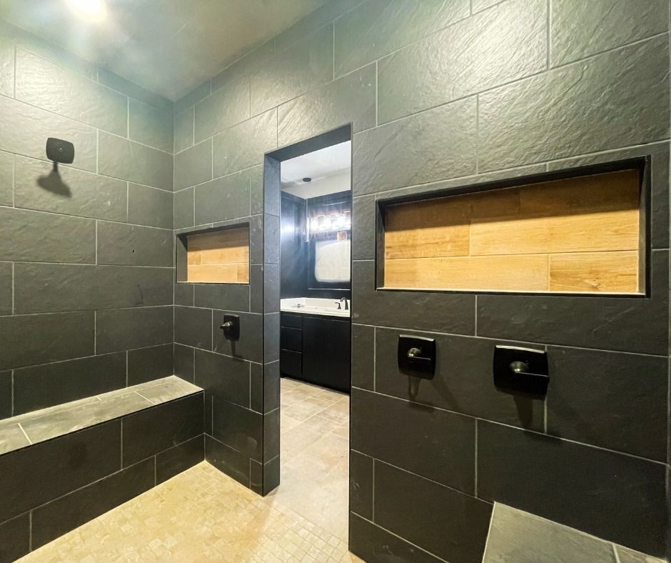 A bathroom with black tiles and wooden niches.