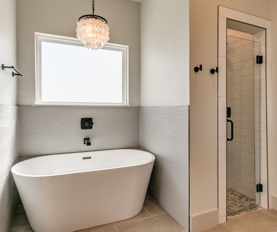 a bathroom with a bathtub , shower , and window