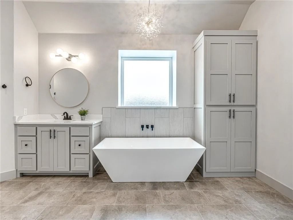 a bathroom with a bathtub , sink , mirror and cabinets