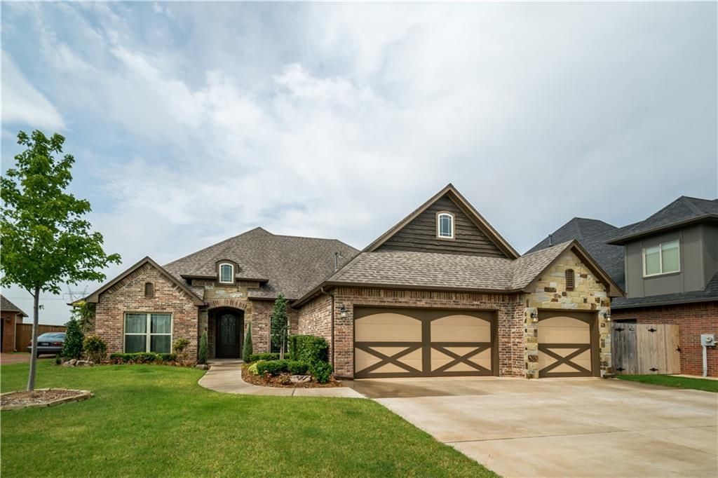 A large brick house with two garage doors in front of it