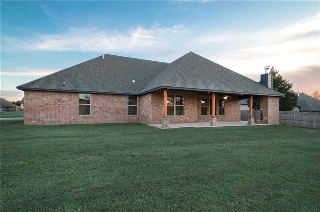 The back of a brick house with a large lawn in front of it
