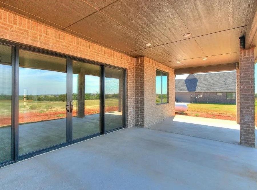A large patio with sliding glass doors and a brick wall.