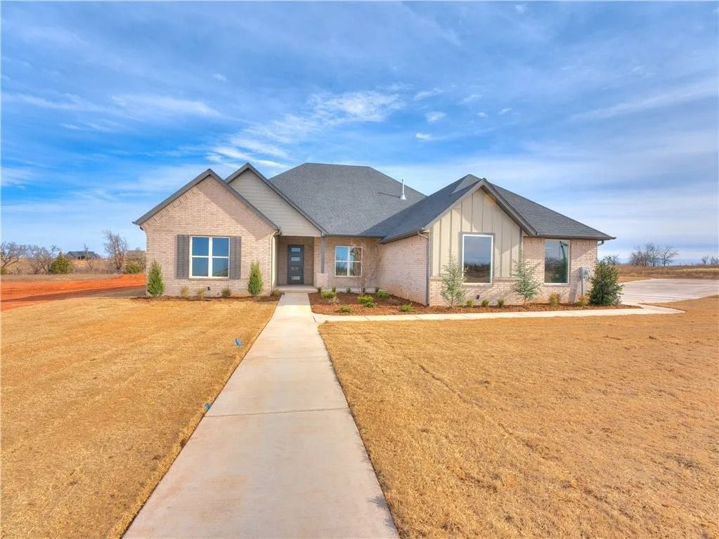 A large brick house with a concrete walkway leading to it.