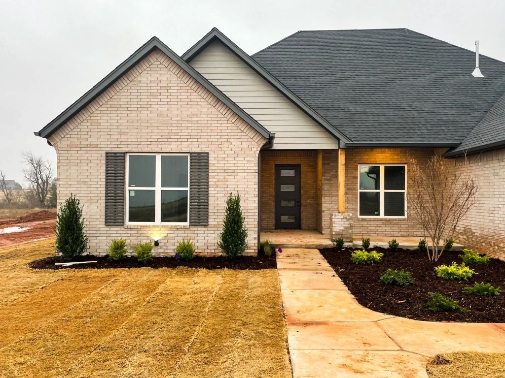 A brick house with a gray roof and a walkway leading to it.