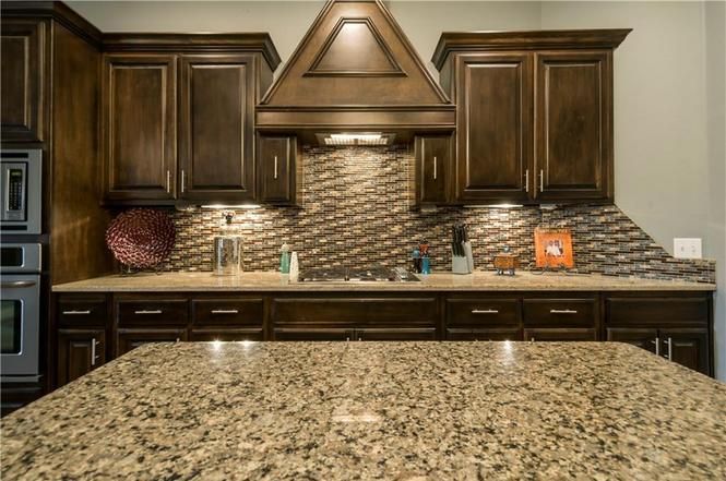 A kitchen with granite counter tops and wooden cabinets.