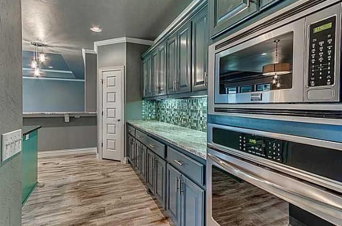 A kitchen with stainless steel appliances and gray cabinets.