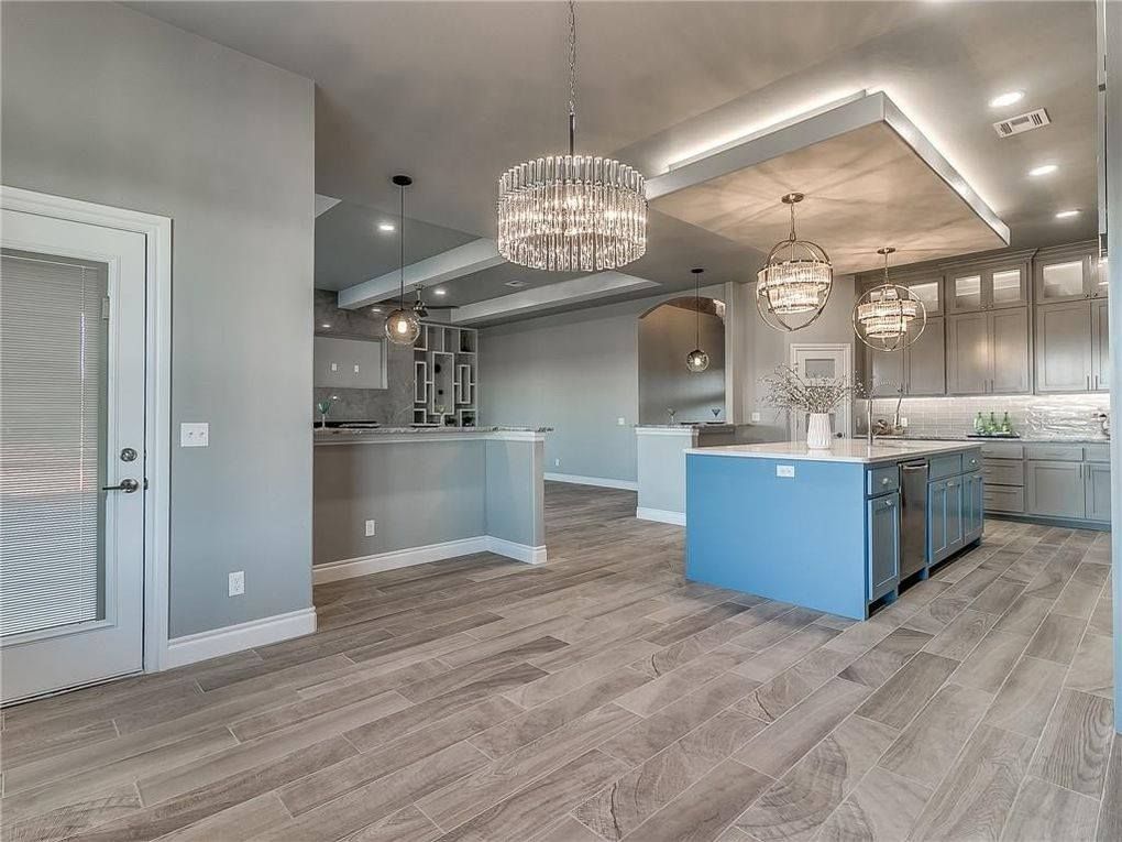 A kitchen with a blue island and a chandelier hanging from the ceiling.