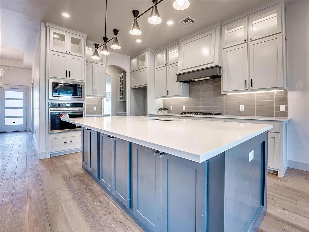 A kitchen with white cabinets and a large island in the middle.