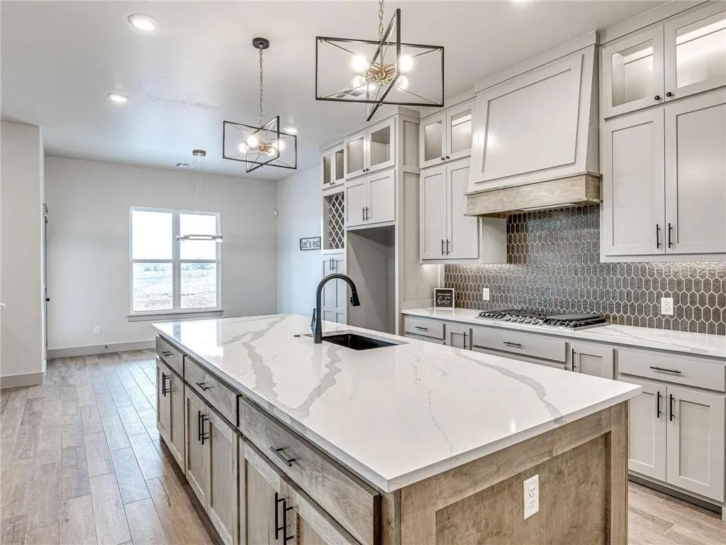 A kitchen with white cabinets and a large island in the middle.