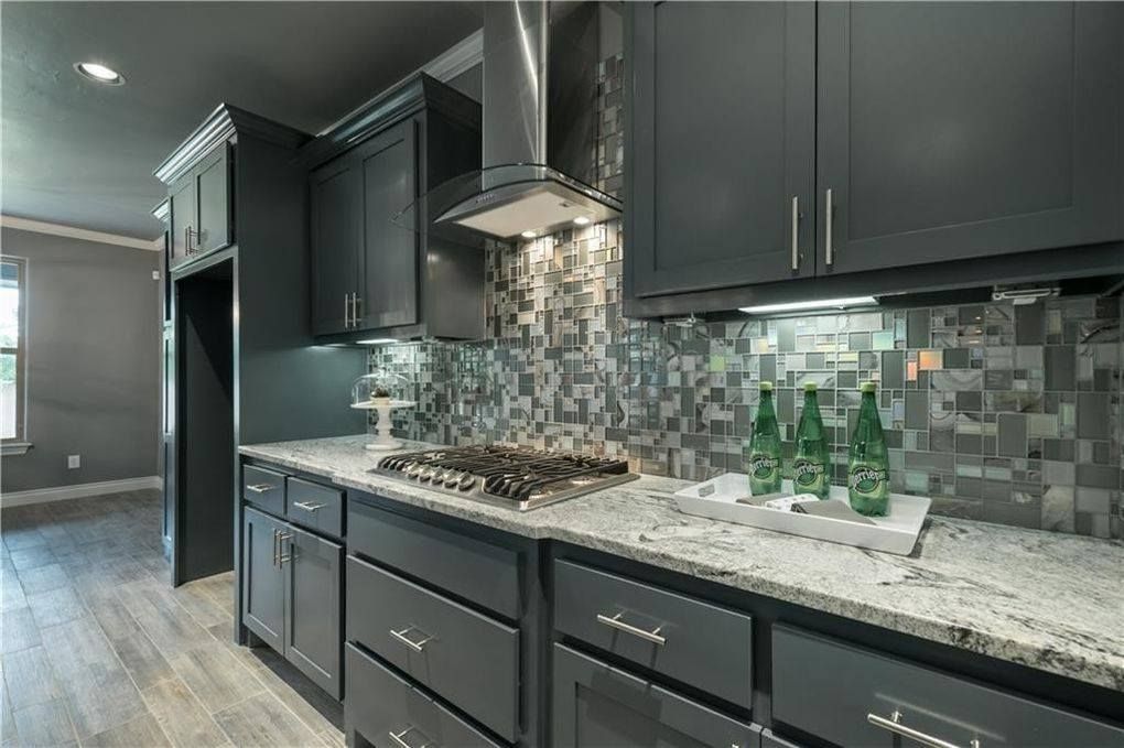 A kitchen with gray cabinets and granite counter tops