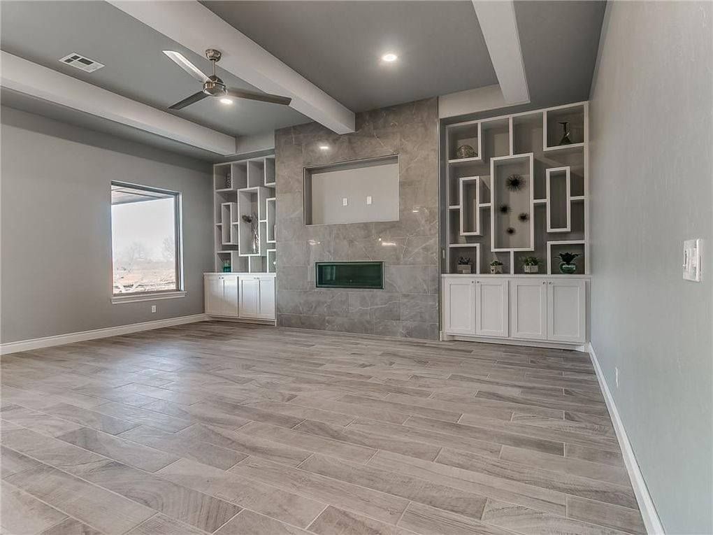 An empty living room with a fireplace and a ceiling fan.