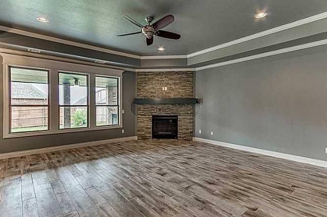 A living room with hardwood floors , a fireplace and a ceiling fan.