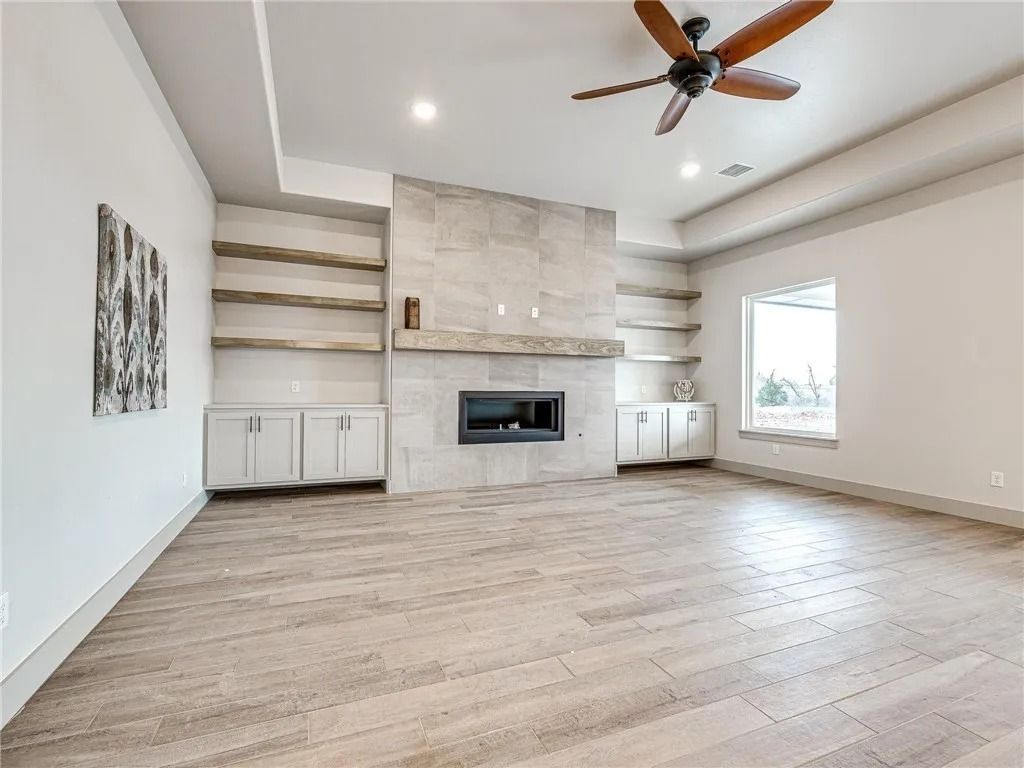 An empty living room with a fireplace and a ceiling fan.