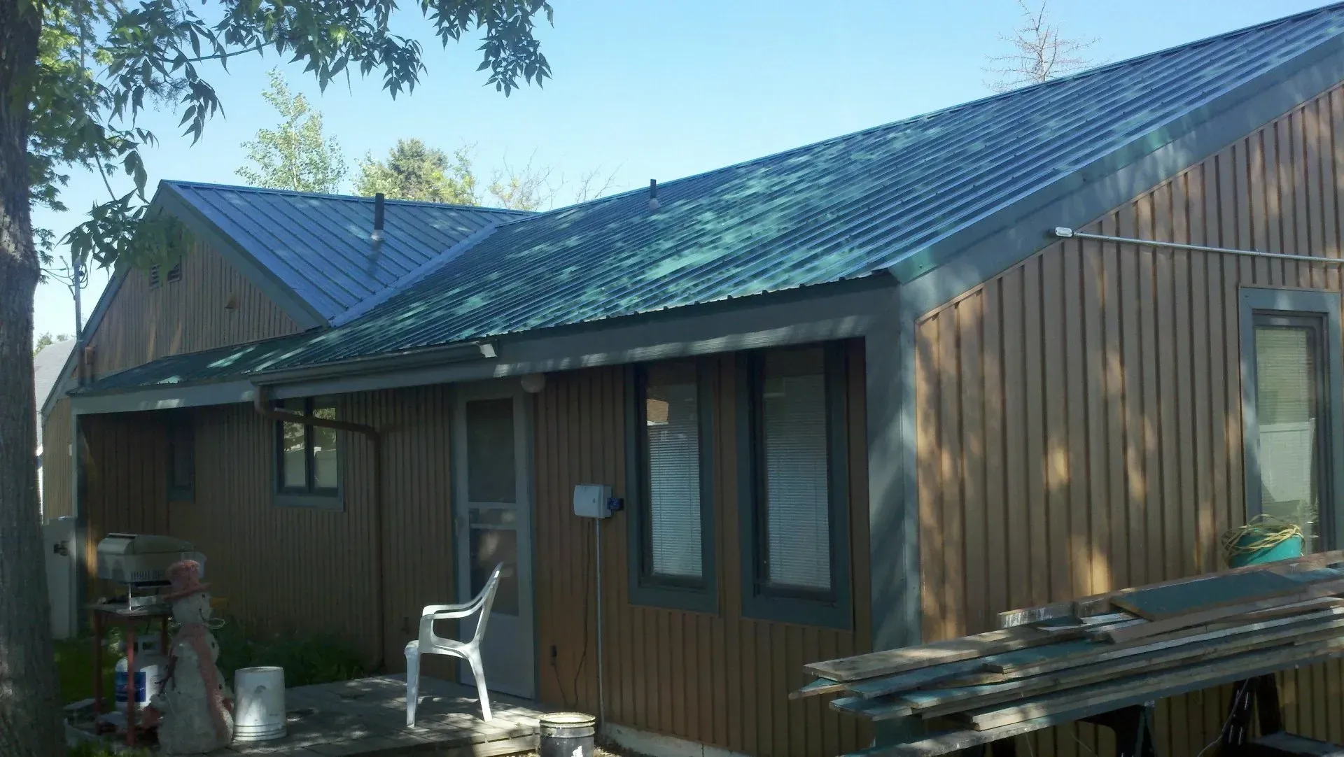 A house with a green roof and a white chair in front of it.