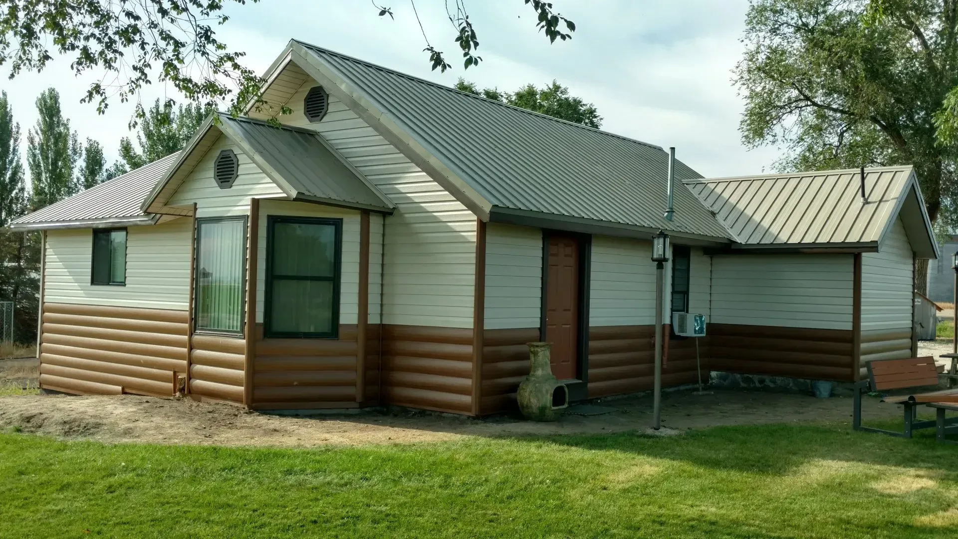 A small house with a log siding and a metal roof