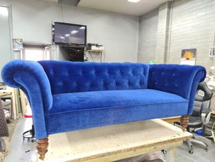 Blue velvet Chesterfield sofa in a workshop.