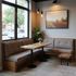 Corner booth with wood table, benches, and a small stool in a cafe setting.