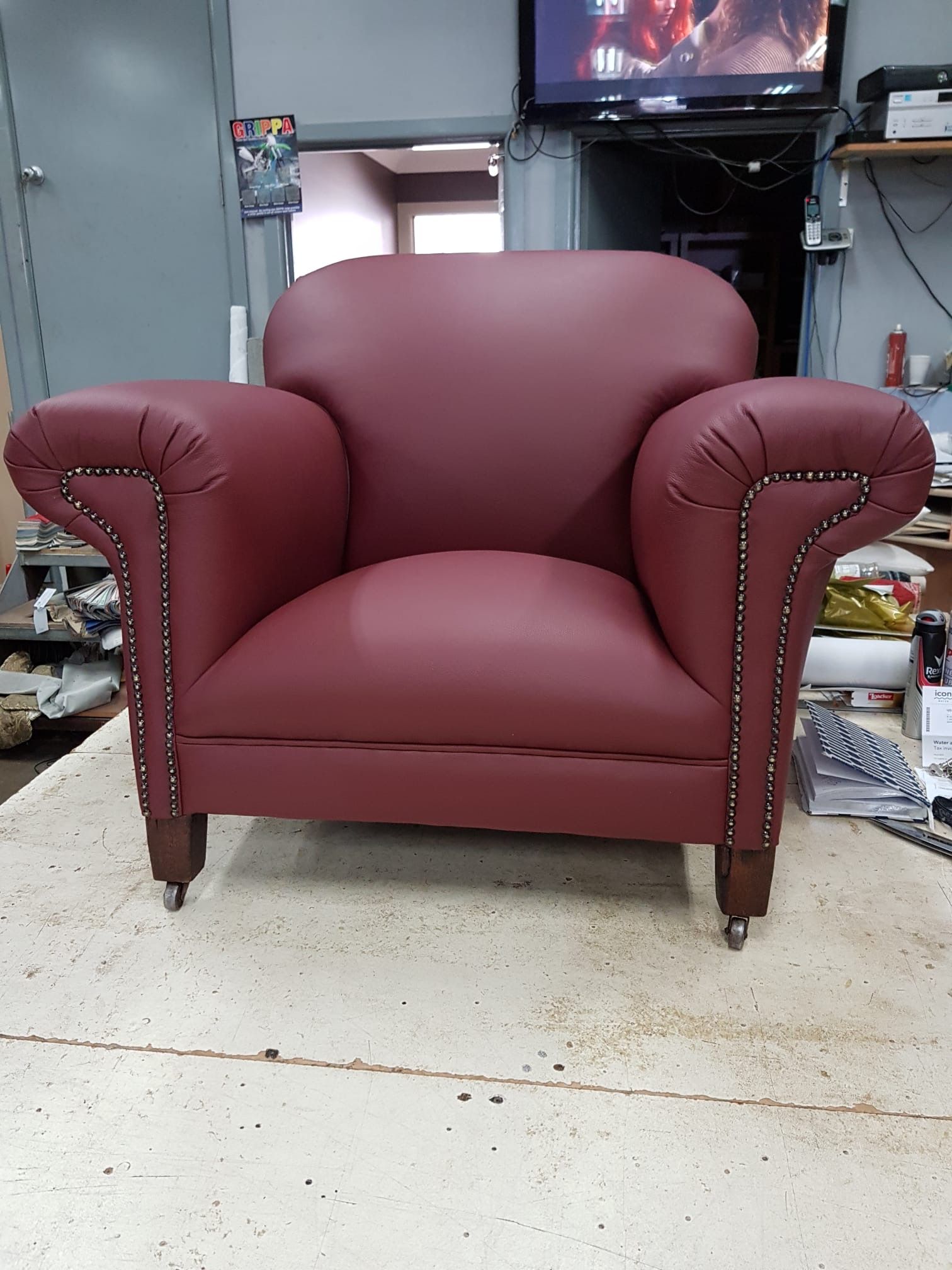 Burgundy leather armchair with studded arms, on a work surface.