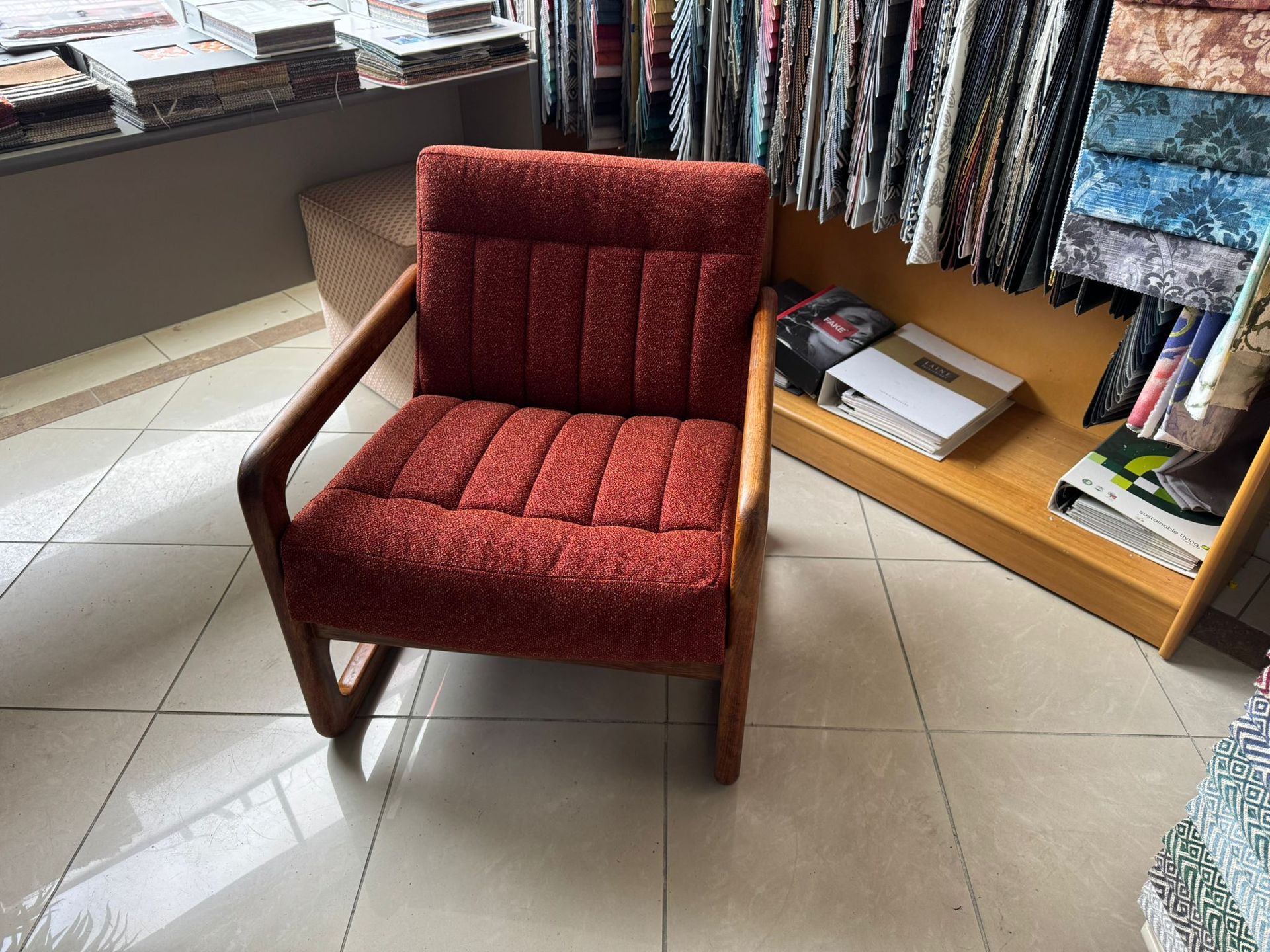 Red upholstered armchair with wooden frame in a fabric store.