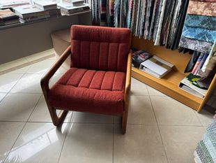 Red upholstered armchair with wooden frame in a fabric store.