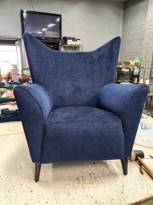 Blue upholstered armchair with curved back and legs.