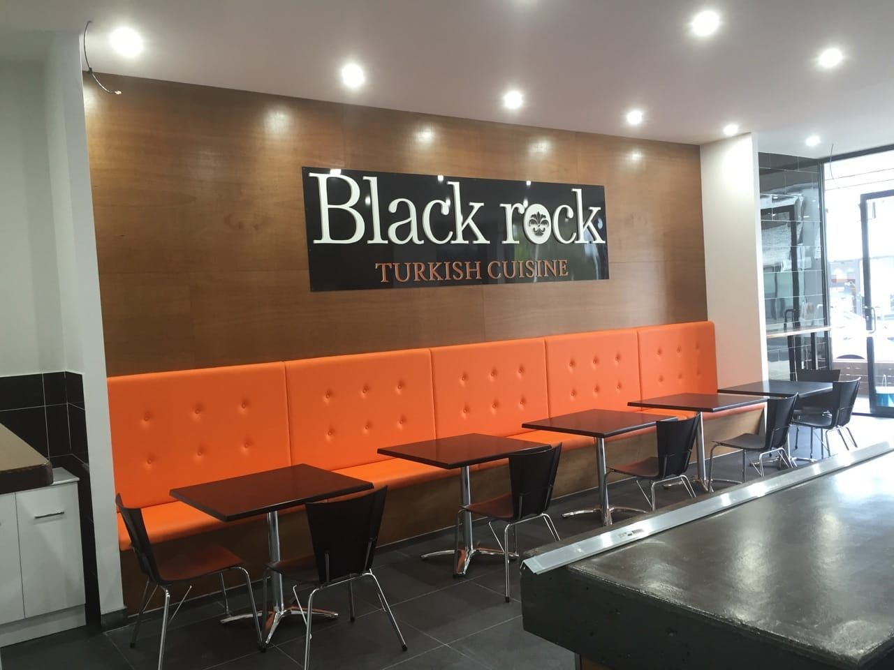 Black Rock Turkish Cuisine restaurant interior with orange seating, brown walls, and tables.