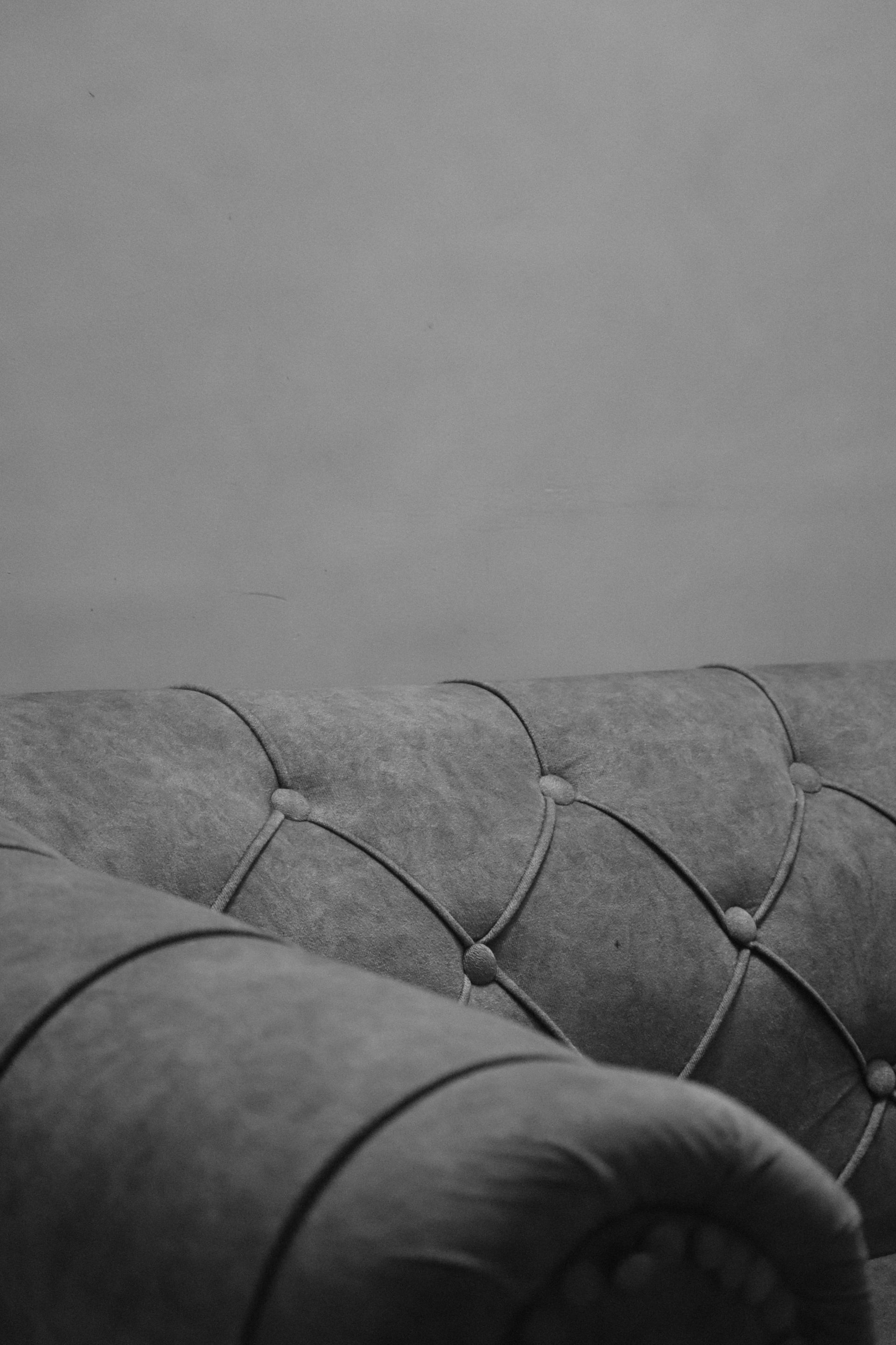 Gray tufted sofa against a gray wall.