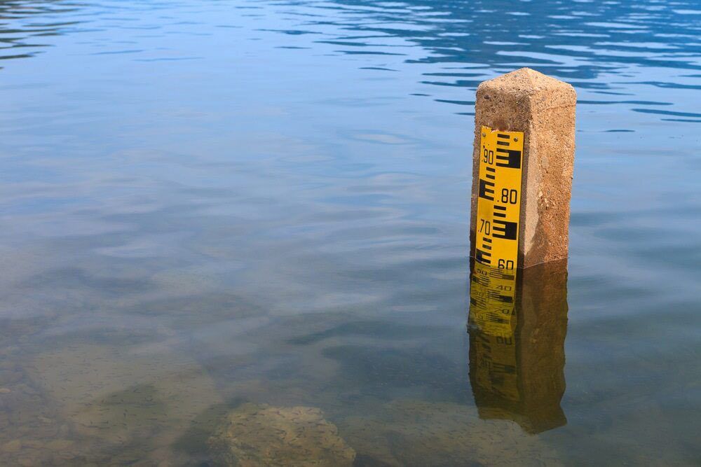 A Concrete Pole In The Water With A Yellow Ruler On It — A2Z Property Services In Woolooga, QLD