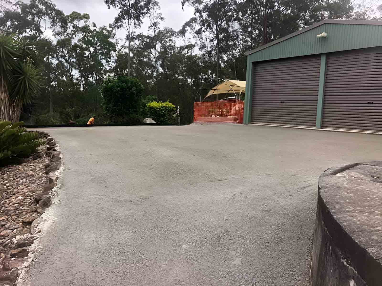A Driveway Leading To A Garage With A Green Building In The Background — A2Z Property Services In Goomboorian, QLD