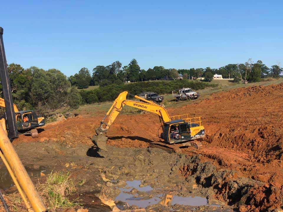A Yellow Excavator Is Digging A Hole In The Dirt — A2Z Property Services In Cooroy, QLD