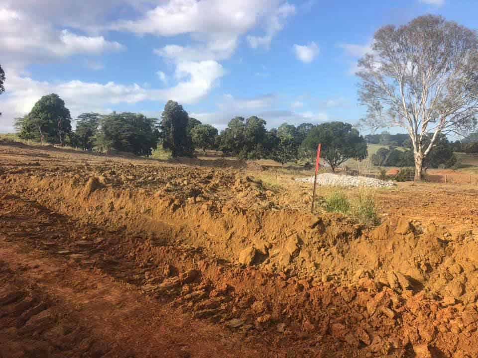 A Dirt Field With Trees In The Background And A Blue Sky — A2Z Property Services In Kybong, QLD