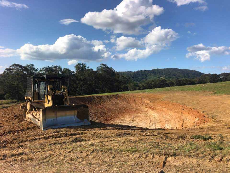 A Bulldozer Is Sitting In The Middle Of A Dirt Field — A2Z Property Services In Kybong, QLD