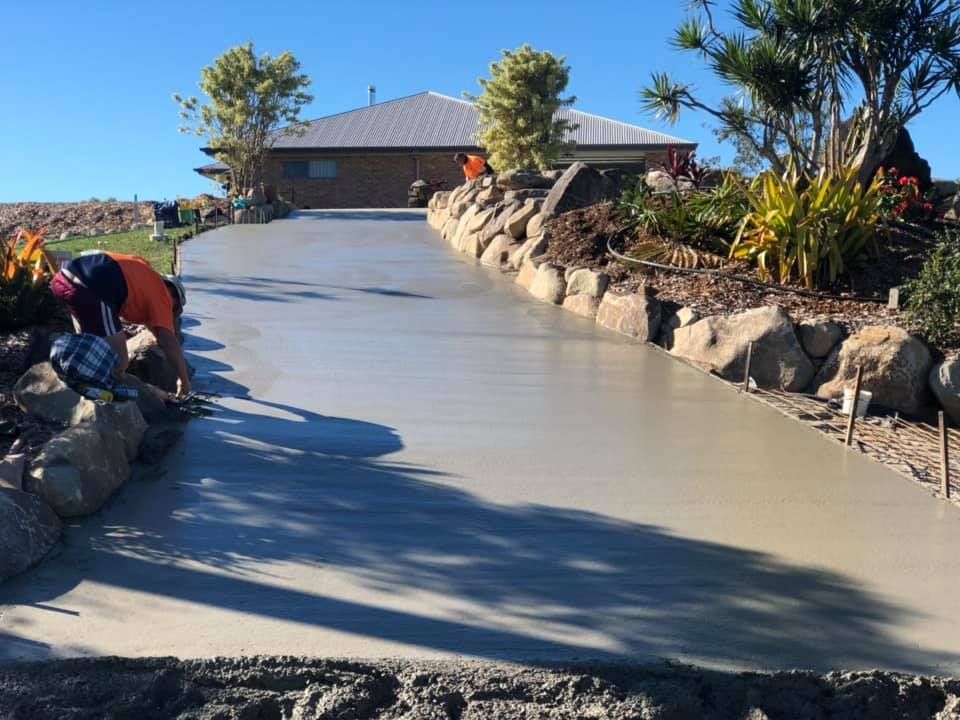 A Man is Working on a Concrete Driveway in Front of a House — A2Z Property Services In Kybong, QLD
